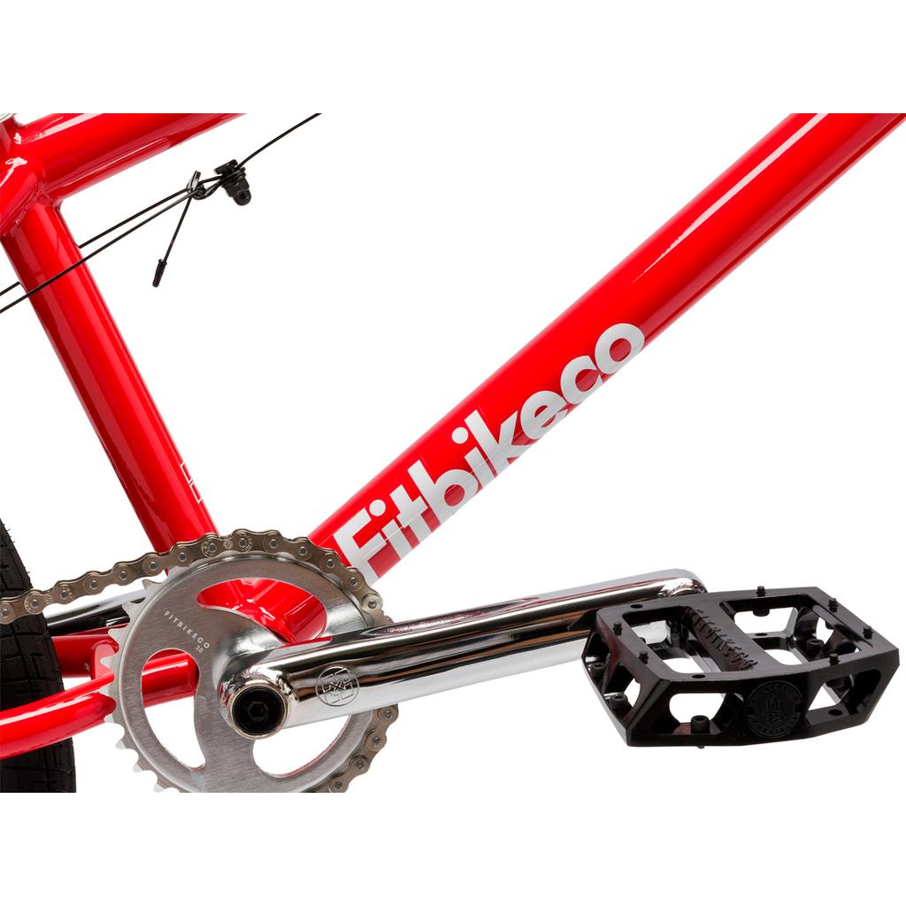 Close-up of a red Fit Bike Co Series 22 Inch Bike frame featuring a silver crank arm, black pedal, partial chainring, and rear tire.