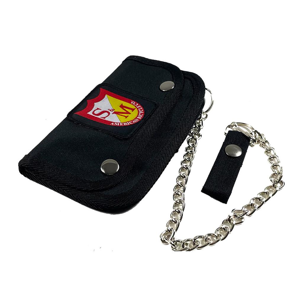 The S&M Trucker Wallet is a black wallet with a snap closure, adorned with a red emblem and securely attached to a silver chain.