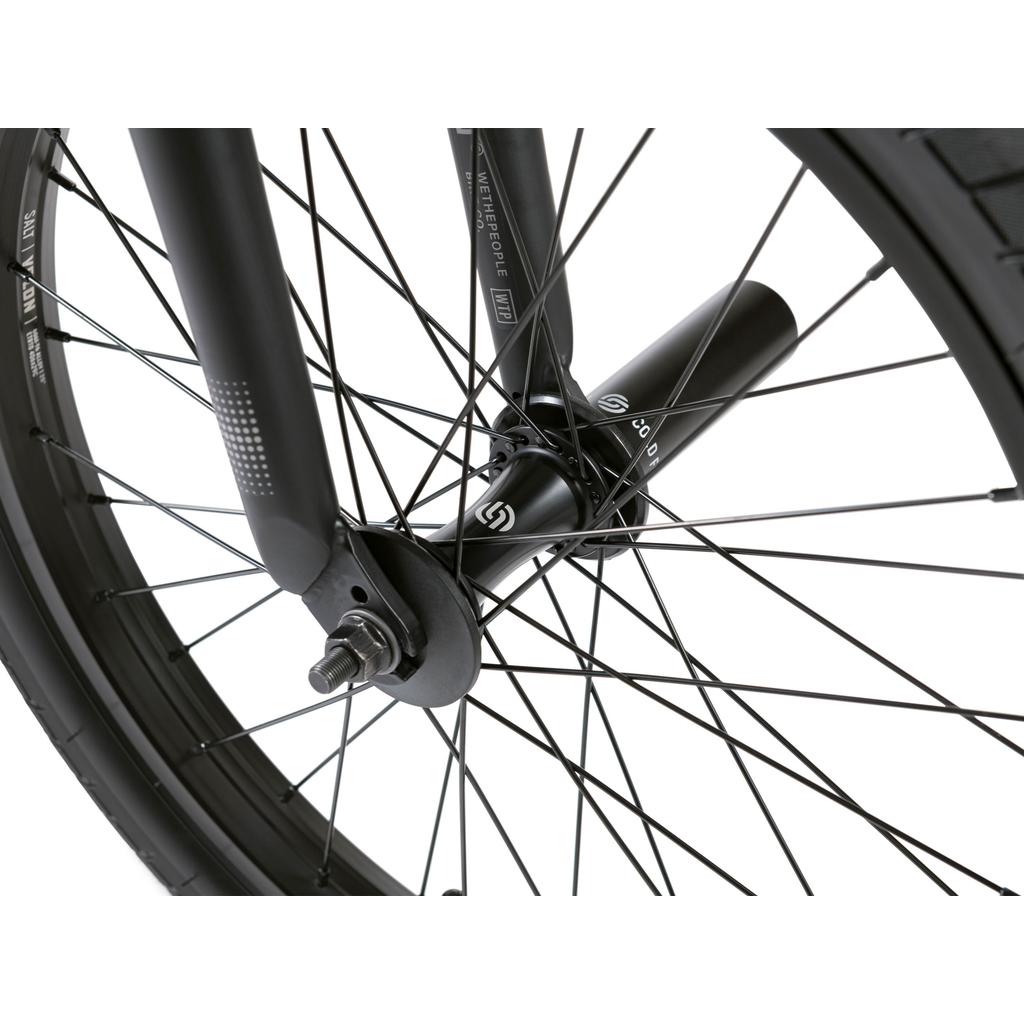 Close-up of the Wethepeople Reason Shift 20 Inch Bike’s front wheel featuring black spokes, axle bolts, and a black hub guard firmly mounted to the fork on a full chromoly frame.