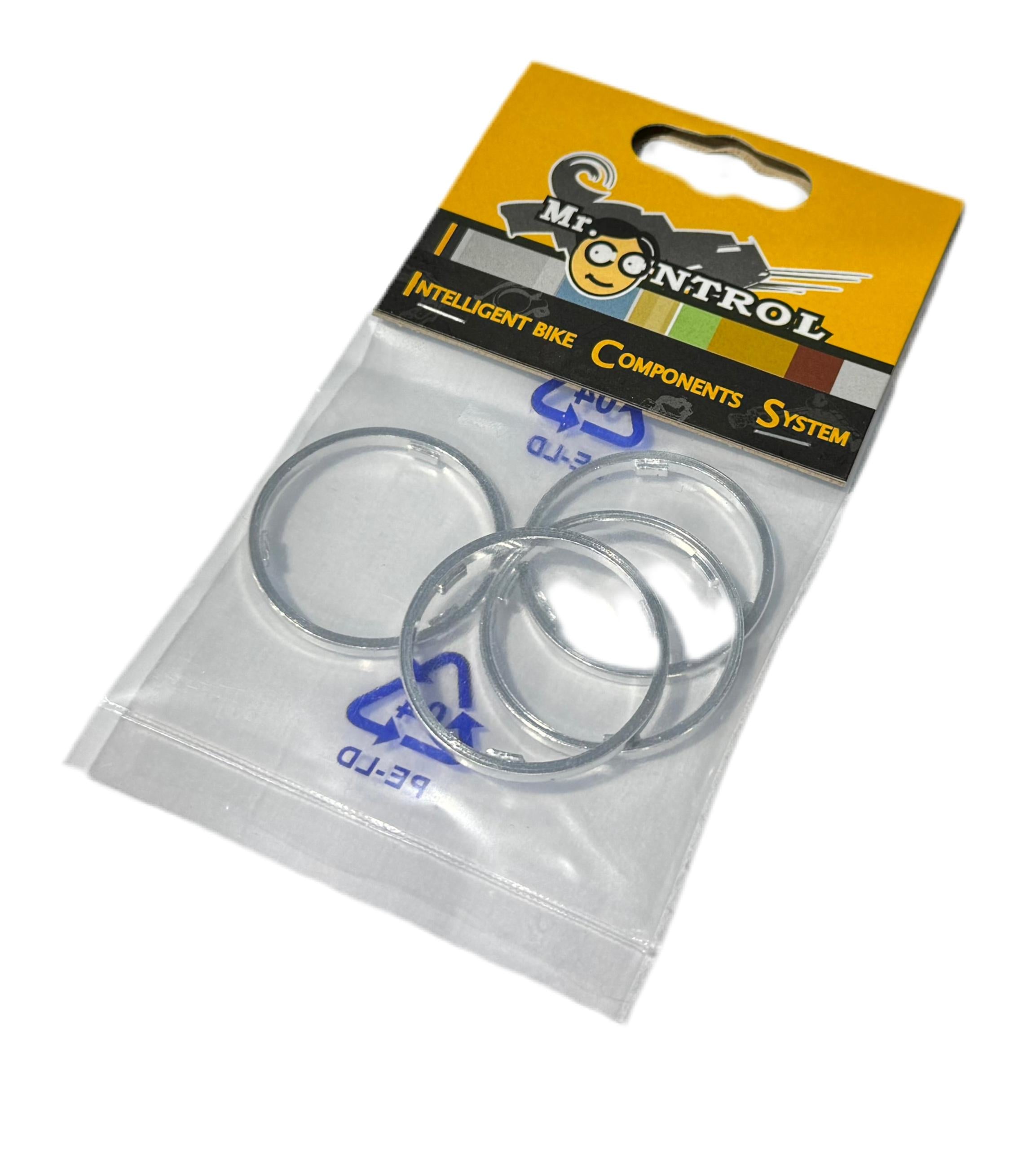 A retail package labeled "Cassette Body Spacer Shimano (4 Pack)" contains four silver cassette body spacers in a clear plastic bag.