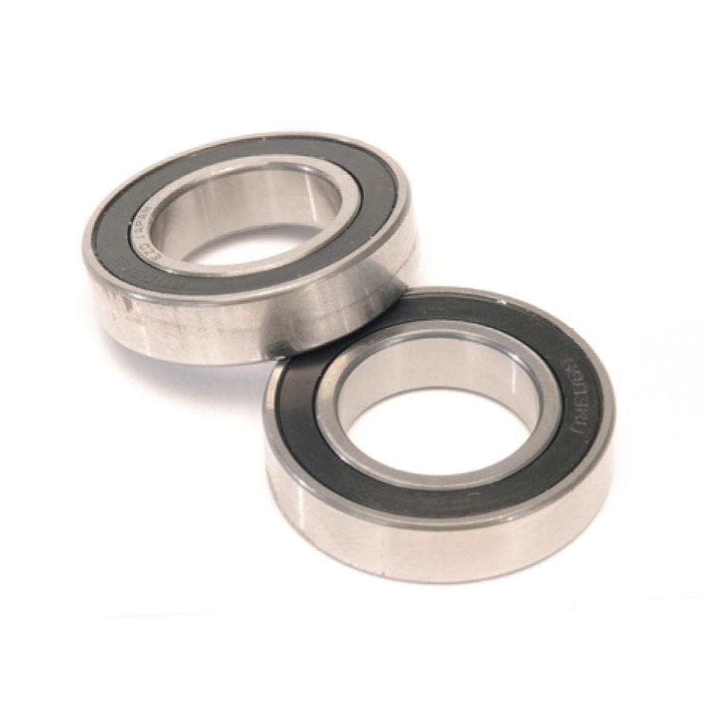 The Eclat Dynamic Hub Bearing Set, featuring two metal hub bearings with black rubber seals, is displayed on a white surface with one bearing partially atop the other—perfect for replacing Eclat Dynamic Hub bearings.