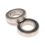 The Eclat Dynamic Hub Bearing Set, featuring two metal hub bearings with black rubber seals, is displayed on a white surface with one bearing partially atop the other—perfect for replacing Eclat Dynamic Hub bearings.