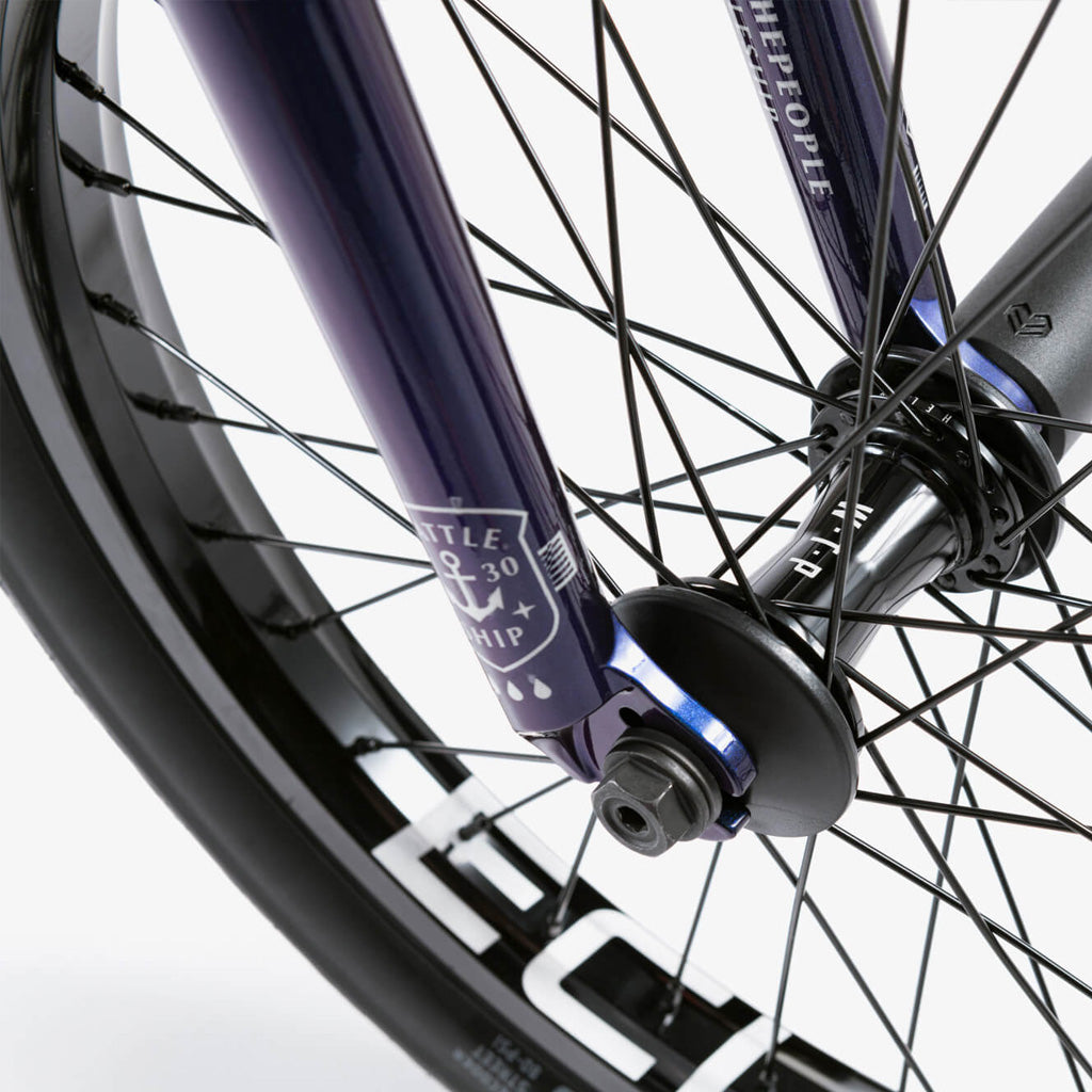 A close up of a purple BMX wheel with black spokes featuring the Wethepeople Battleship 20 Inch BMX Bike.