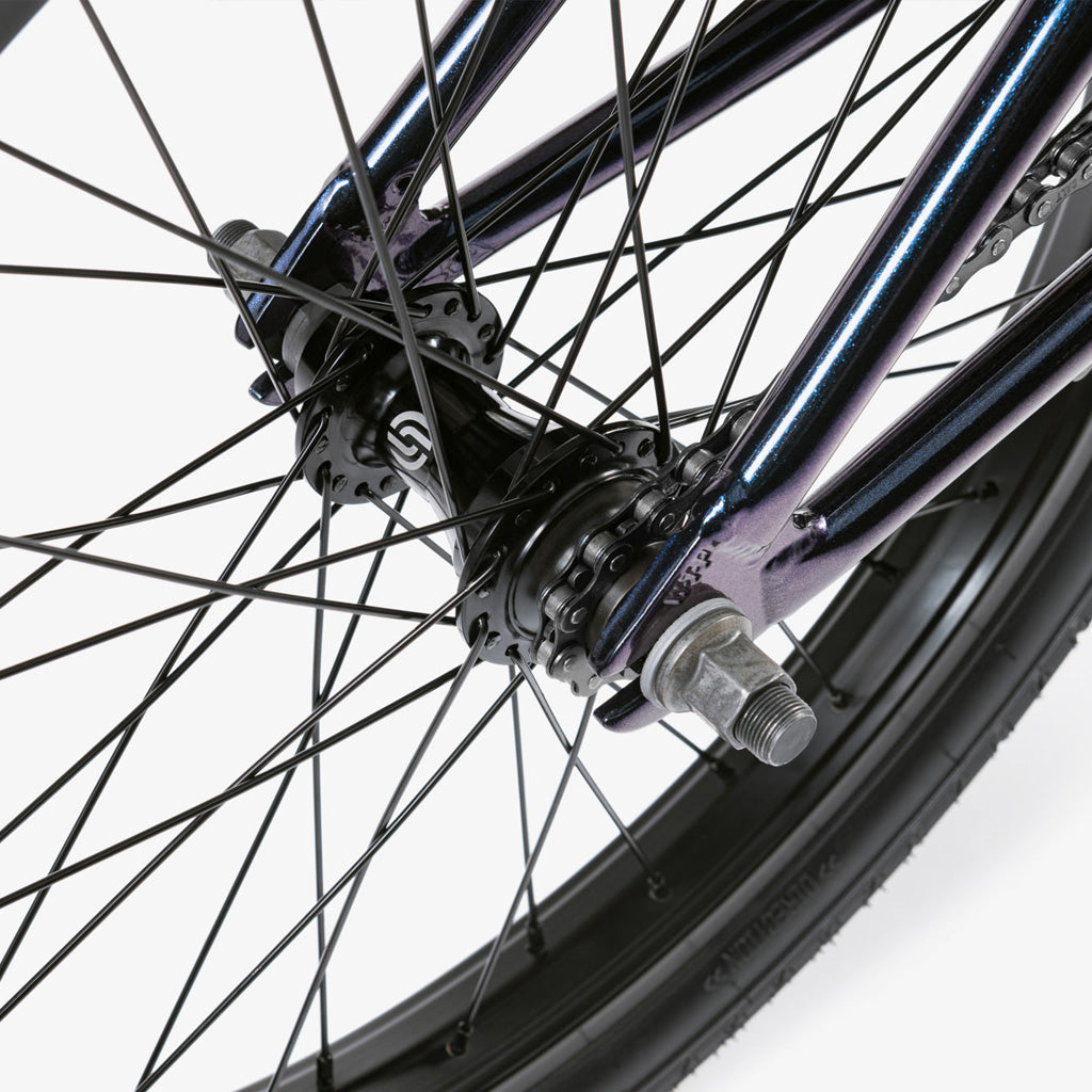 A close up of a bmx bike with purple spokes featuring the Wethepeople CRS 20 Inch Bike equipped with Salt Rookie Chromoly Three Piece Cranks and Eclat Surge Pedals.