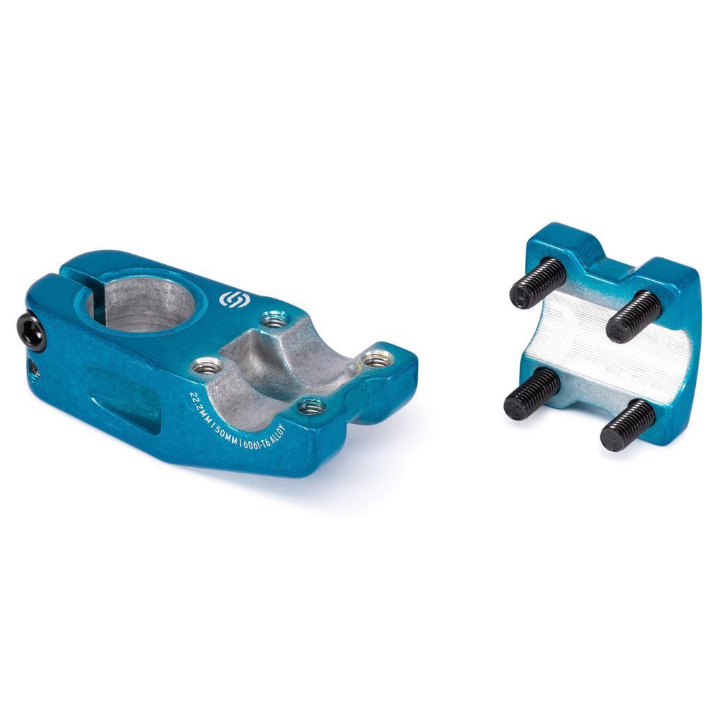 The Salt Am V2 Top Load Stem (22.2mm Clamp) is a blue metal BMX stem crafted from durable 6061 T6 alloy, featuring bolt holes and displayed alongside its matching clamp plate with four screws on a white background. This stem incorporates shark tooth clamping for a secure grip.