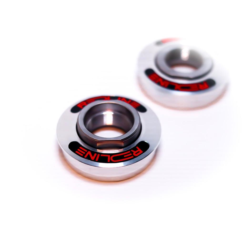 Close-up of two metallic circular components with "REDLINE" in red on black, featuring a central hole and smooth finish—Redline Techmatic USA BB Set, compatible with Redline Flight Crank and Techmatic Bottom Bracket systems.