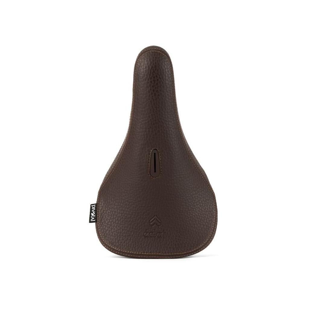 The Eclat Exile Pivotal Seat is an ergonomic brown leather bicycle saddle featuring a central cutout and a small black label on the left side, displayed against a white background.