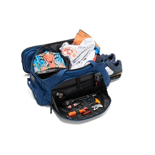 The Albek Skytrail 51 Gear Bag in blue features multiple compartments, including a padded helmet section, and opens up to reveal clothing, gear, and organized smaller items like tools and accessories.