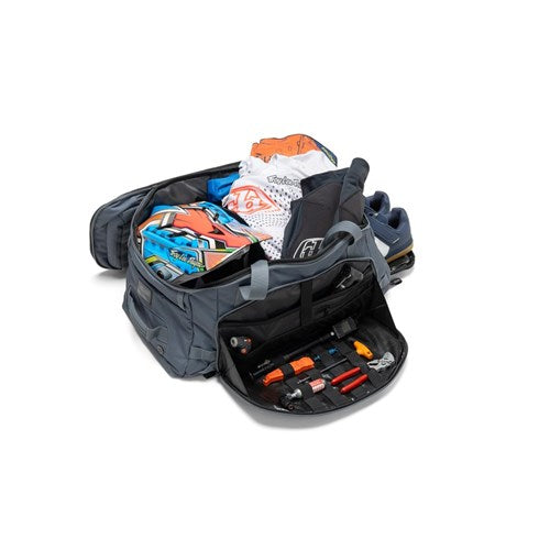 An Albek Skytrail 51 Gear Bag sits open, displaying folded clothes, shoes, and various small tools and accessories neatly arranged in its interior gear storage pockets.