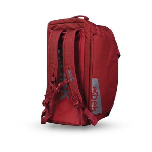 The Albek Skytrail 51 Gear Bag, a red backpack with padded shoulder straps, side handle, and zippered gear compartments, stands upright on a white background.