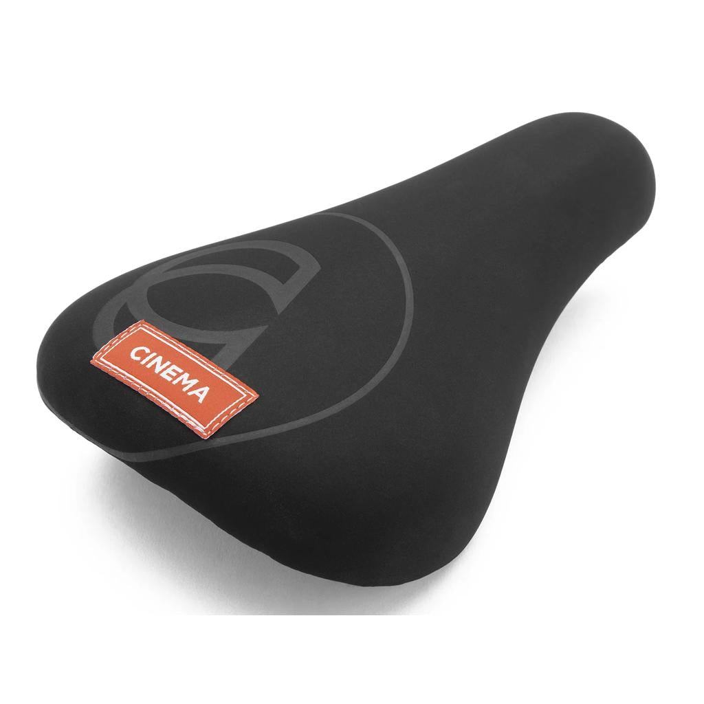 The Cinema Press Stealth Seat features a sleek black design with a subtle logo pattern and a red "CINEMA" patch on the rear, crafted from microfiber-like material.