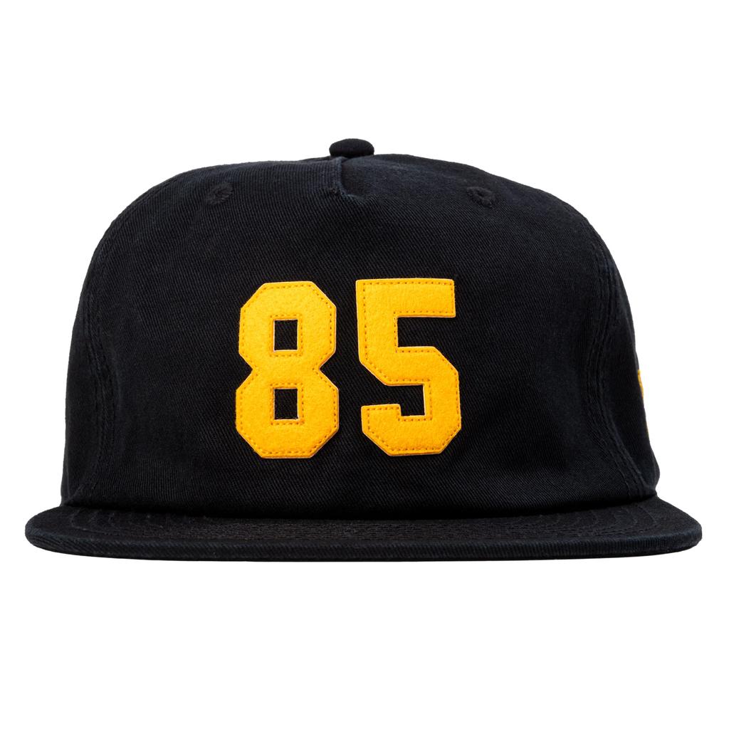 The Odyssey 85 Cap is a sleek black 5-panel hat with the yellow number 85 embroidered on the front—perfect for your Back to School 2025 style.
