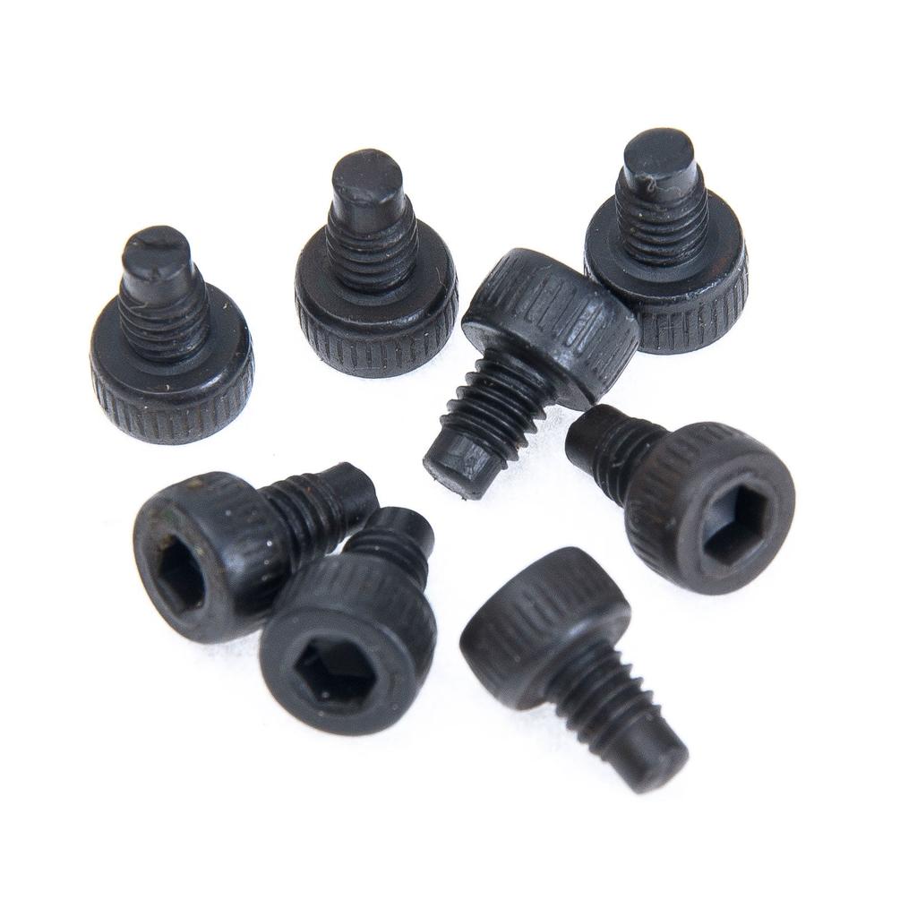 Eight black metal hex socket screws, ideal as replacement pedal pins for Eclat Slash pedals, are arranged on a white surface—some standing upright, others lying on their sides.