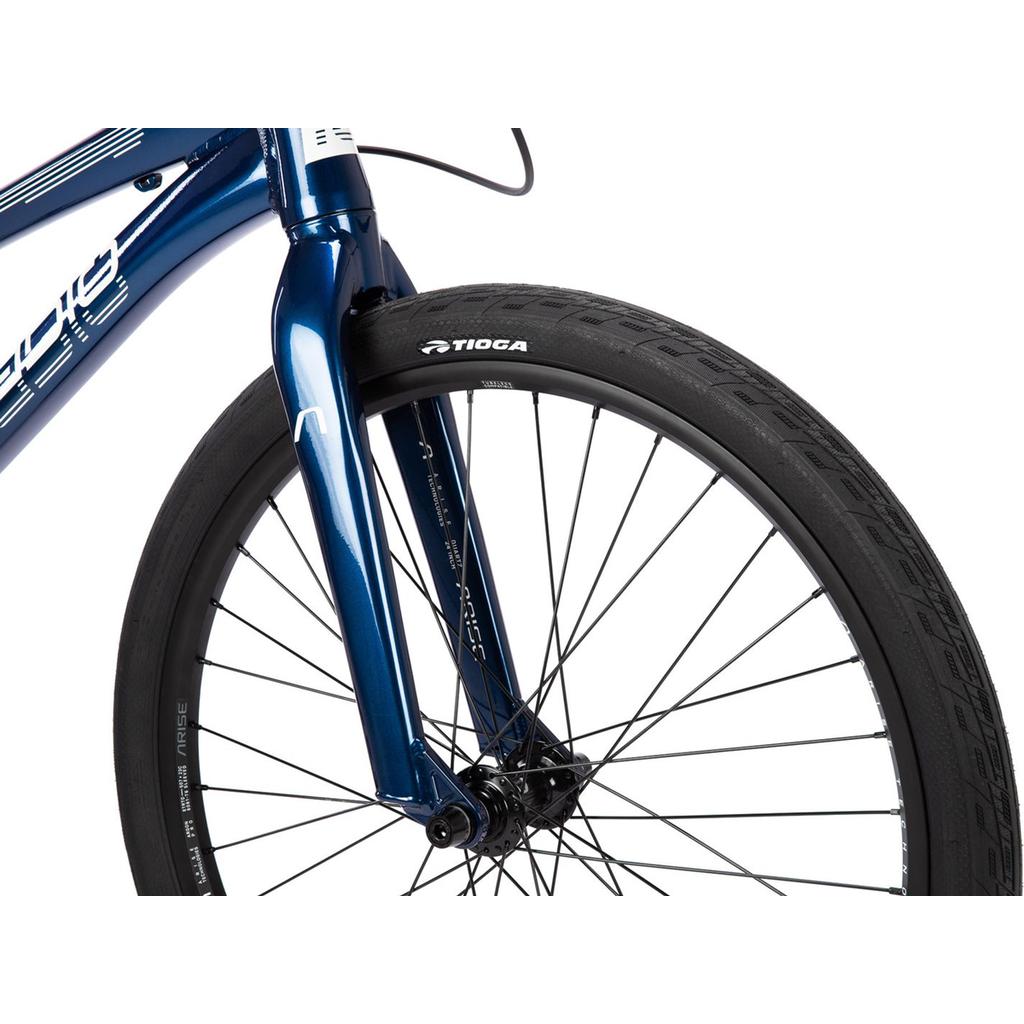 Close-up of the front wheel and fork on the Radio Raceline Quartz Pro Disc 24 Inch Bike, featuring black spokes, a Tioga tire, and blue frame with white graphics and race-oriented geometry.