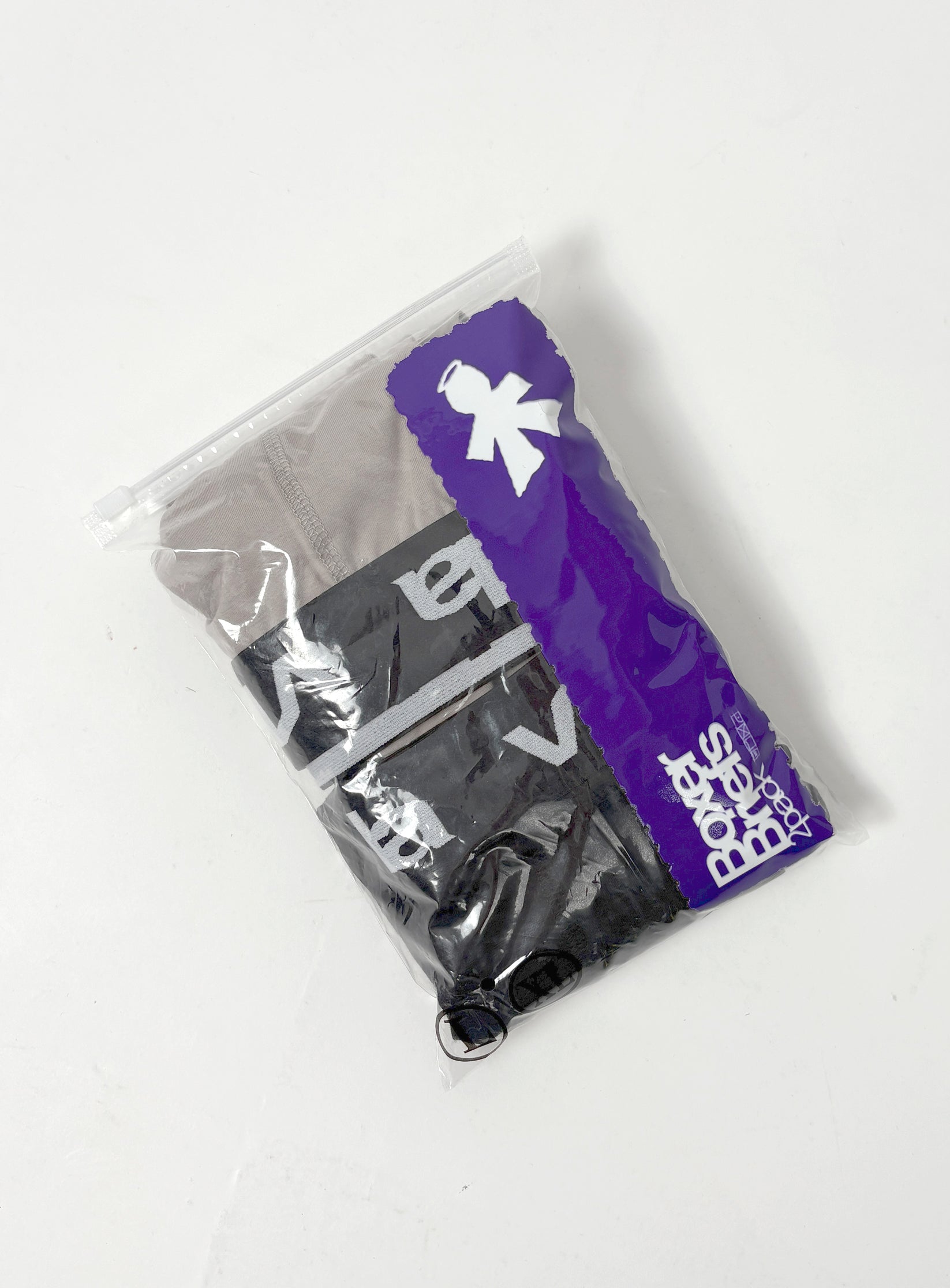 A clear plastic bag with a purple stripe contains V1da Boxer Briefs (2 Pack) in black and gray, featuring visible white lettering and an updated mid-length design.