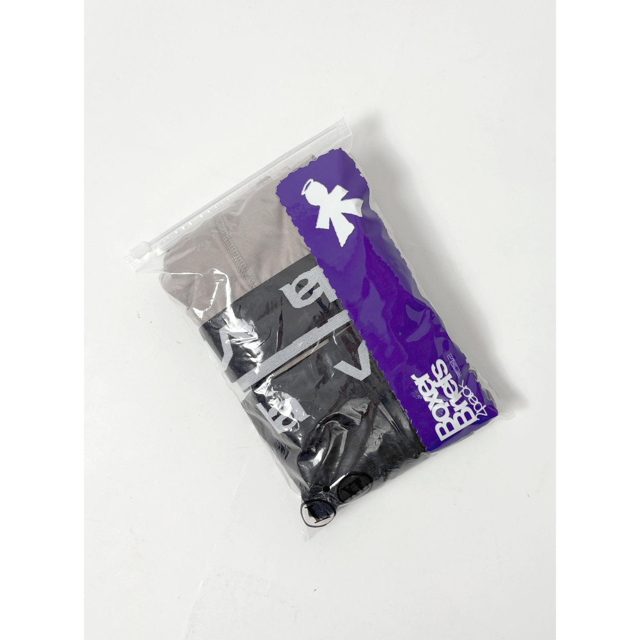 A clear plastic bag with a purple stripe contains V1da Boxer Briefs (2 Pack) in black and gray, featuring visible white lettering and an updated mid-length design.