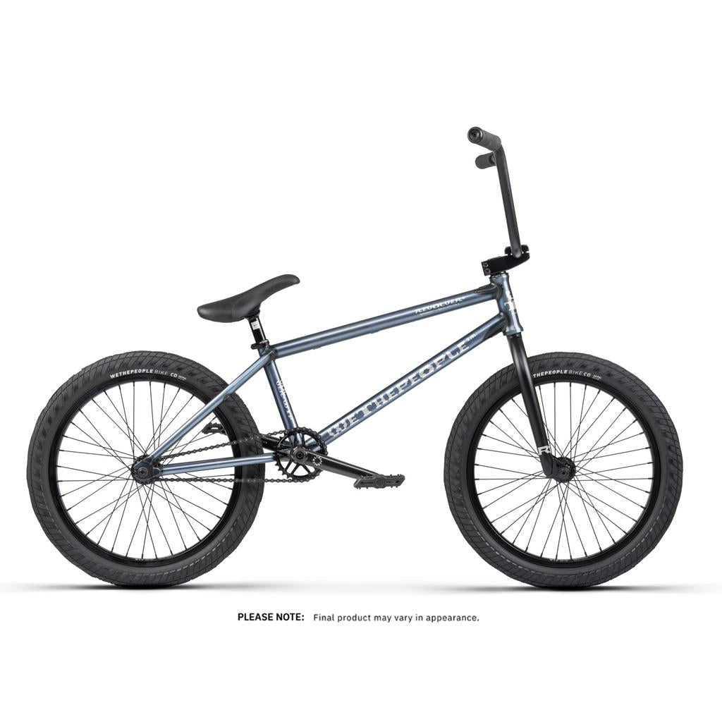The Wethepeople Revolver 20 Inch Bike is shown in profile on a white background, with a metallic blue frame, black saddle, handlebars, pedals, and tires, featuring high-end components for top performance.