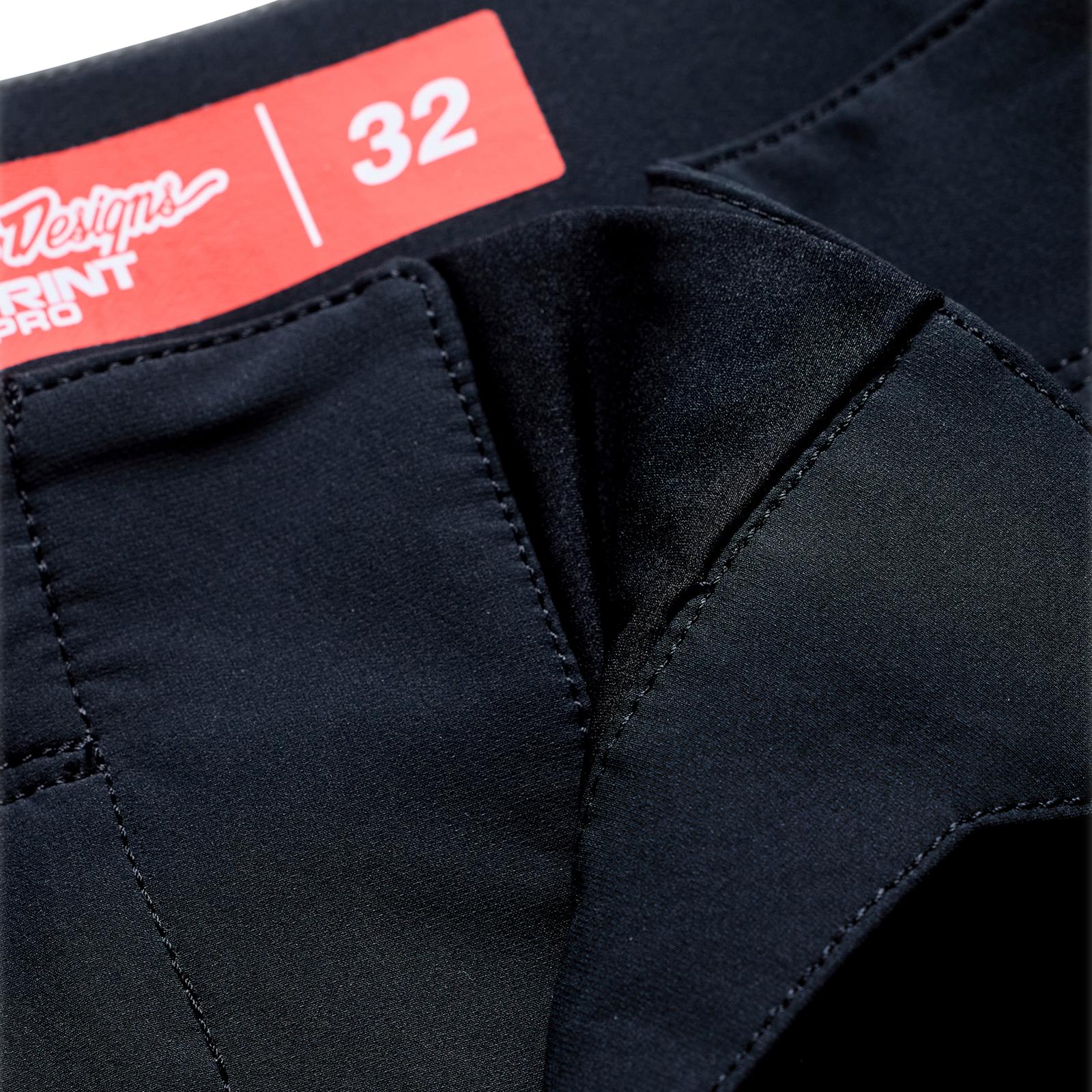Close-up of TLD 26.1 Sprint Pro Pants / Mono Black, featuring a visible seam and red size 32 label on the waistband, crafted from lightweight poly mesh for enhanced ventilation.