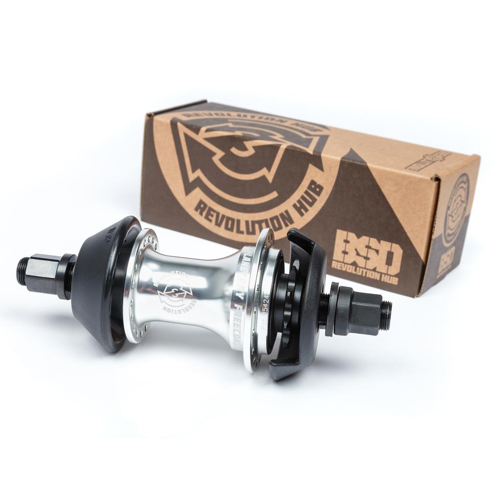 The BSD Revolution Rear Freecoaster Hub showcases a chrome design with black components, packaged in a brown box labeled "BSD Revolution Hub." It features an innovative planetary clutch system for smooth and efficient operation typical of high-quality free coaster hubs.