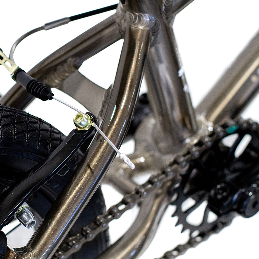 Close-up image of a Colony Horizon 14" Micro Freestyle Bike from the Colony Horizon series, focusing on the chain, gear mechanism, and brake cable of its lightweight alloy frame.