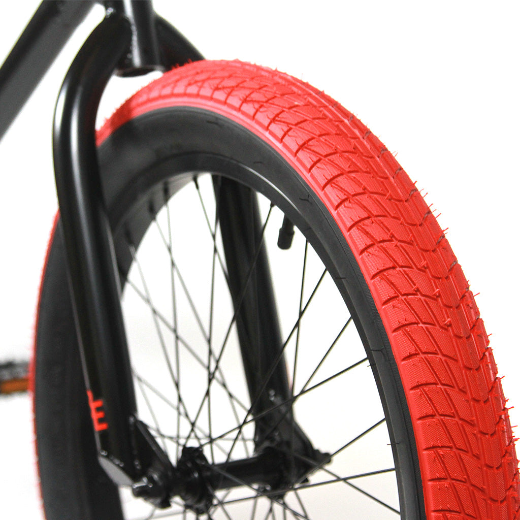 A close up of a Black Eye Kilroy 20 Inch Bike with a red tire.
