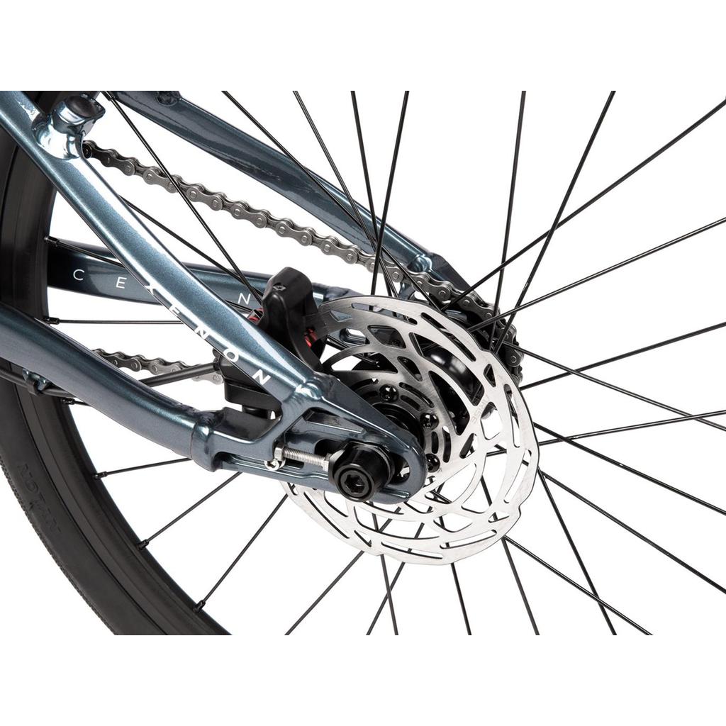 Close-up of a bicycle rear wheel showing disc brake rotor, caliper, chain, and part of the frame with "Radio Xenon Expert Disc 20 Inch Bike" branding, highlighting its lightweight alloy frame and sealed cassette drivetrain.