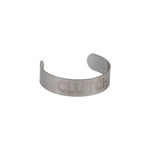 The Odyssey Clutch Hole Adjust Cover, a silver metal accessory engraved with "CLUTCH" and inspired by Odyssey bike parts, is showcased against a white background.