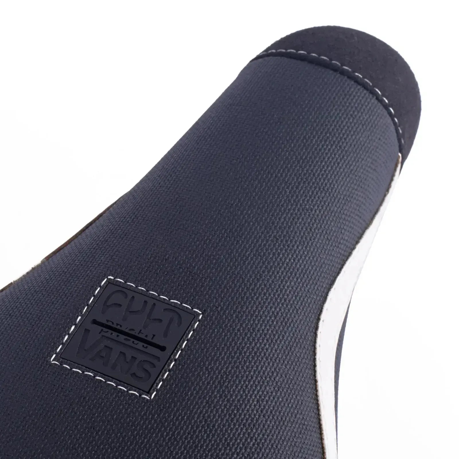 Close-up of the Cult Vans Pivotal Old Skool Pivotal Seat in Black/White, showcasing white stitching and a square "CULT x VANS" logo patch.