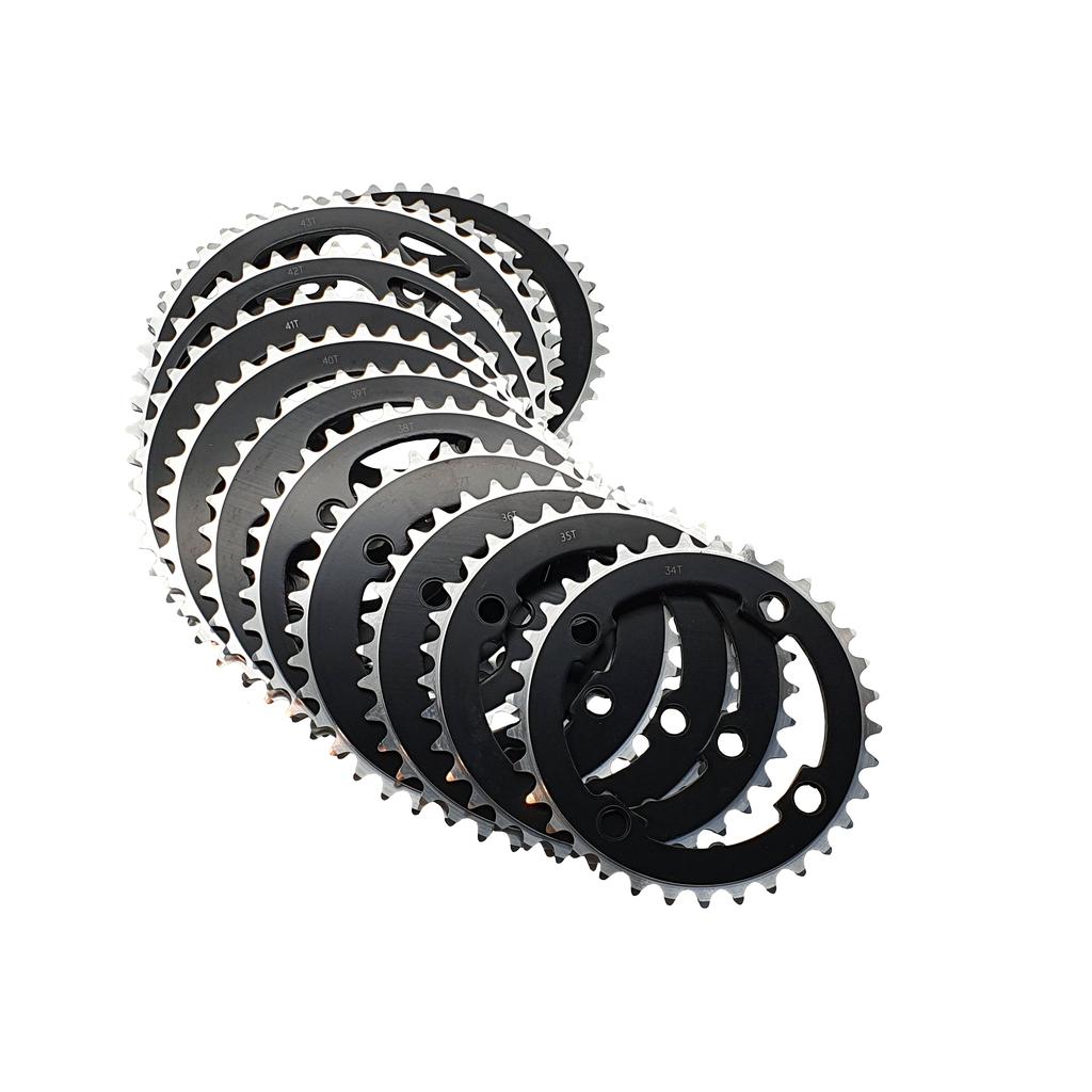 The DRS 104BCD 4 Hole Chainring set features black metal rings with silver teeth, displayed in a staggered, overlapping formation on a white background.