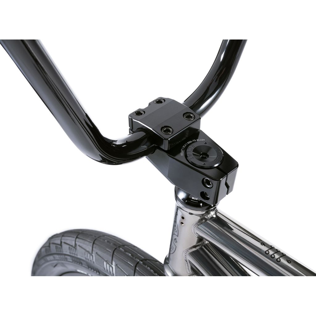 Close-up of a black BMX handlebar and stem attached to the front fork, with a textured tire below. This setup from the Wethepeople Envy 20 Inch Bike collection truly showcases BMX design and performance mastery.