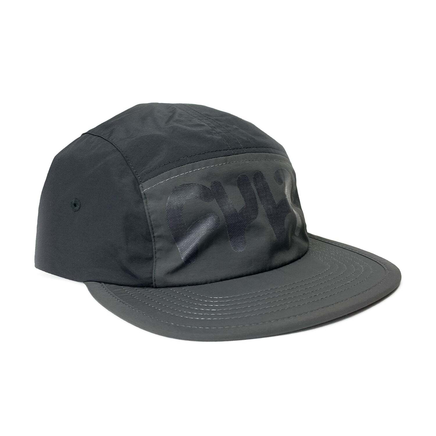 The Cult Runner Cap is a dark gray, low-profile hat made from recycled nylon, featuring a prominent stylized black logo across the front panel and a flat brim.