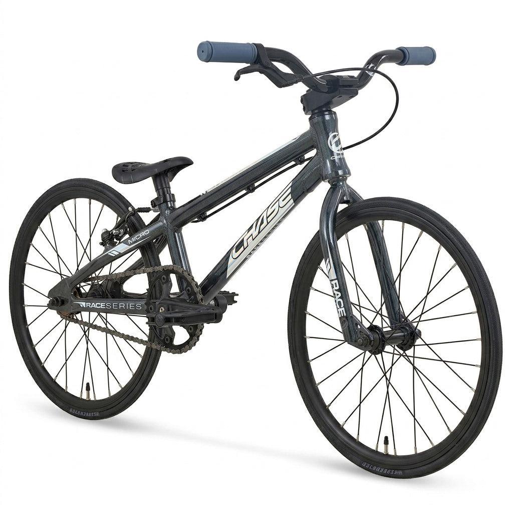 The Chase Race Series Micro 18 Race Bike (2027) is displayed at an angle on a white background, featuring a black and gray color scheme, lightweight frame, large tires, and a padded seat. Designed as an ideal BMX race bike for kids, this model delivers the speed and durability young riders need for the track.