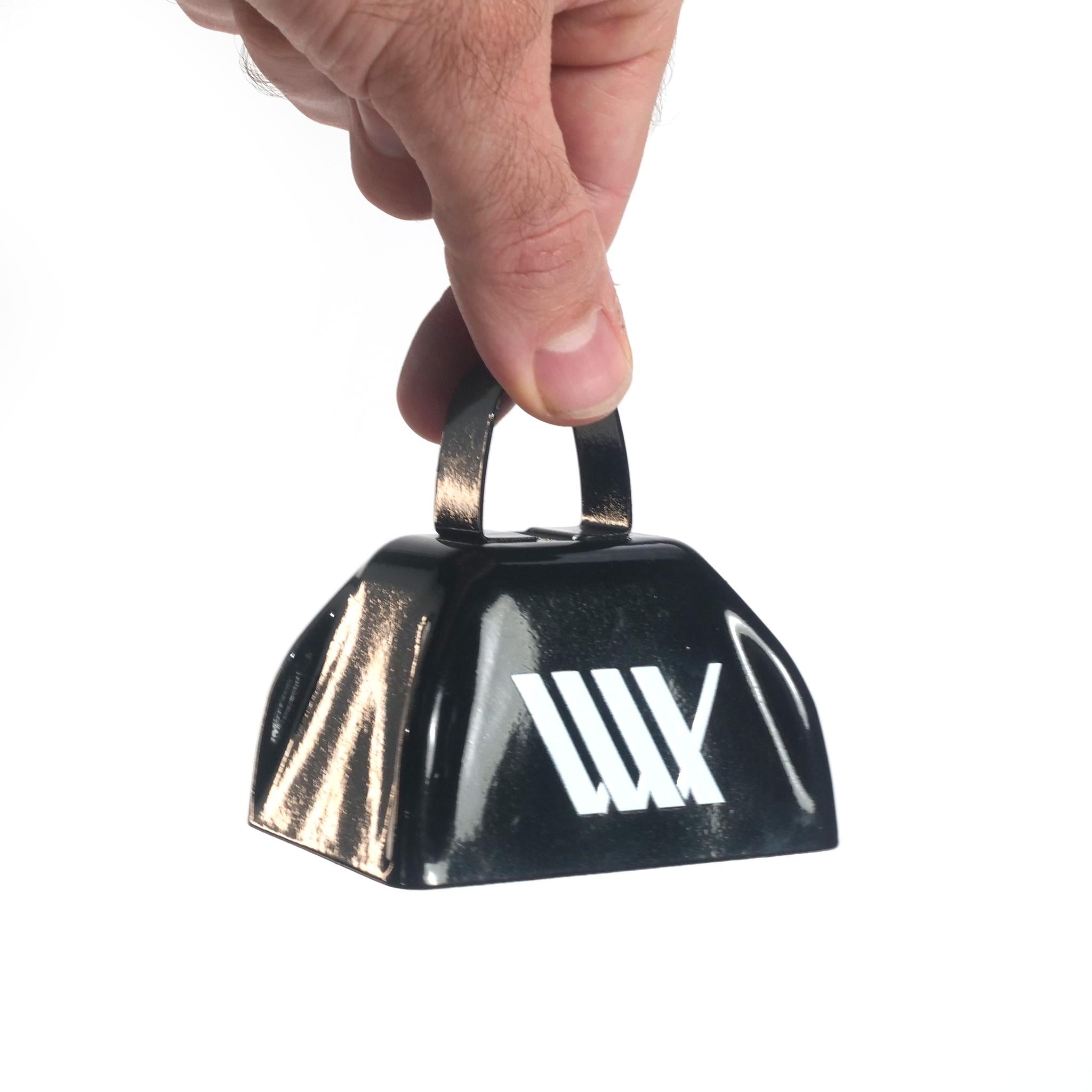 A hand holding the LUXBMX Supporters Cowbell—a compact metal cowbell featuring a white geometric logo on its side, perfect for trackside cheering—against a plain white background.