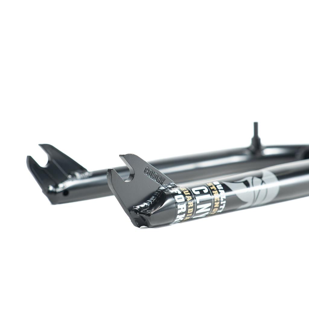 Close-up of Colony Guardian 20 Inch Forks w/ Brake Mounts in black, featuring visible dropouts and graphic decals; made from heat-treated CrMo for enhanced durability.