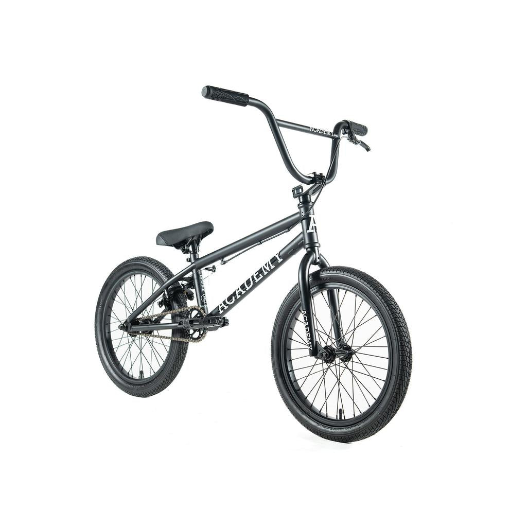 The Academy Inspire 18 Inch Bike is shown on a white background, featuring thick tires, a padded seat, and high handlebars.