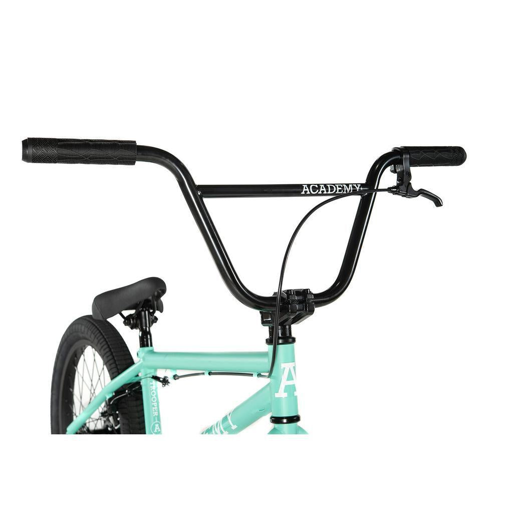 Close-up of black handlebars with "ACADEMY" branding on the Academy Trooper 20 Inch Bike in turquoise, showing part of the seat and frame—ideal for beginner BMX riders.