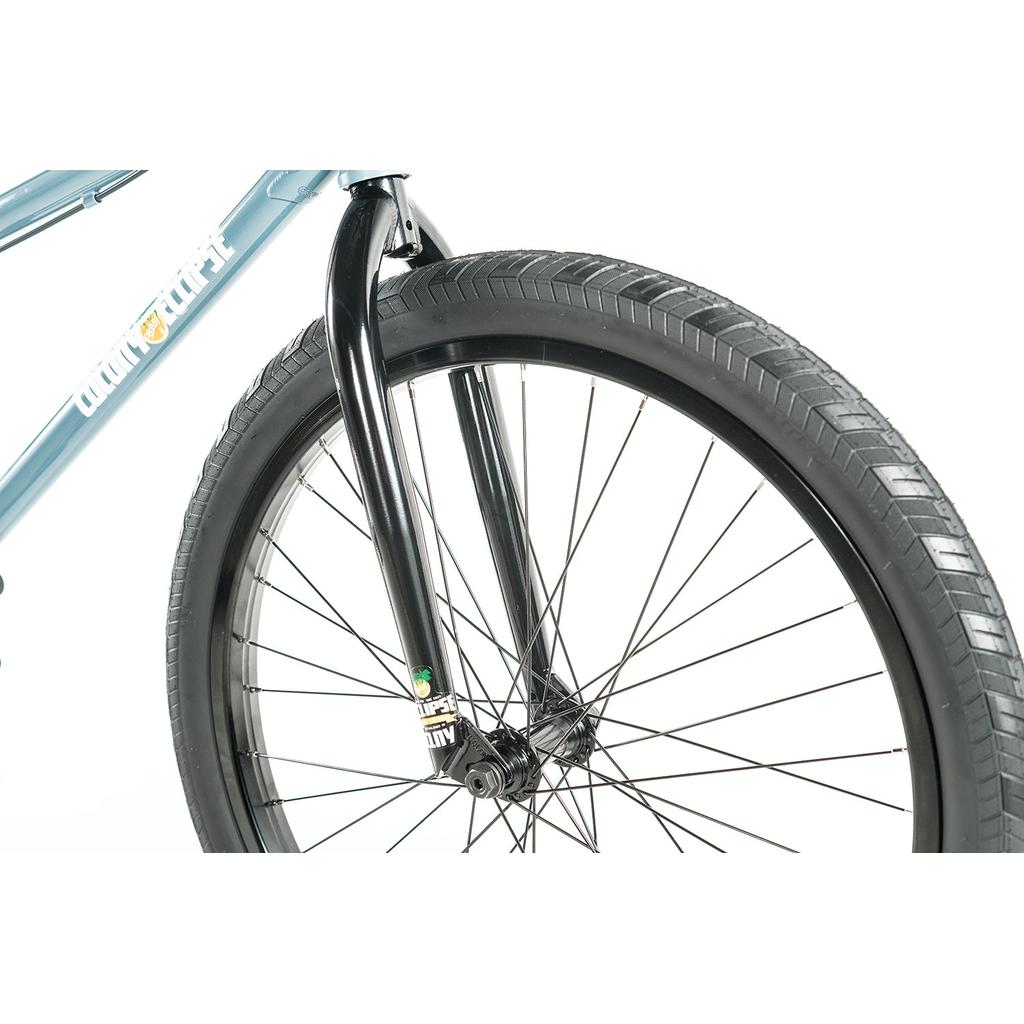 Close-up of the front wheel and black fork, highlighting tire tread, spokes, and part of the blue chromoly frame on the Colony Eclipse 24 Inch Bike against a white background.
