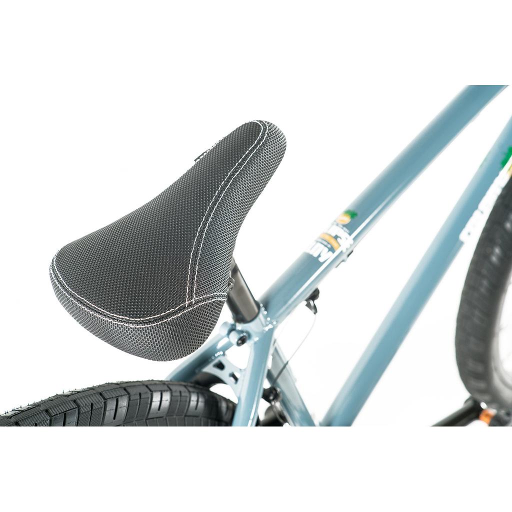Close-up of the black seat with visible stitching and rear wheel on a blue Colony Eclipse 24 Inch Bike, showing part of its chromoly frame.