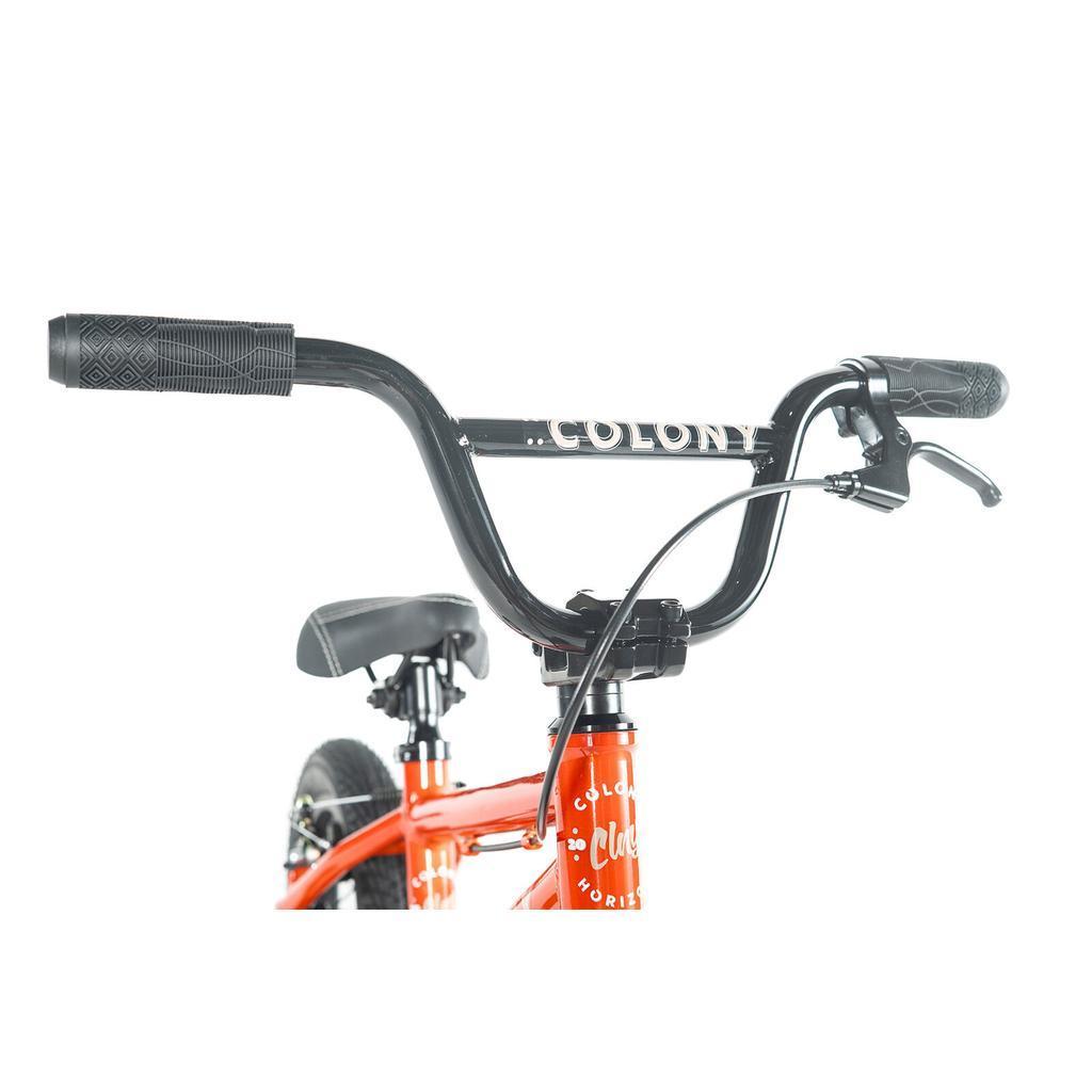 Close-up of the handlebars, brake lever, and front section of a red Colony Horizon 12 Inch Bike featuring "COLONY" branding—showcasing its lightweight alloy frame for agile performance.