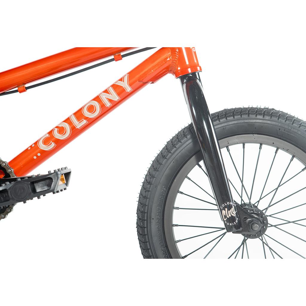 Close-up of the Colony Horizon 14 Inch Bike, featuring an orange frame labeled "COLONY," a black front fork, pedal, and front wheel with detailed tire tread.