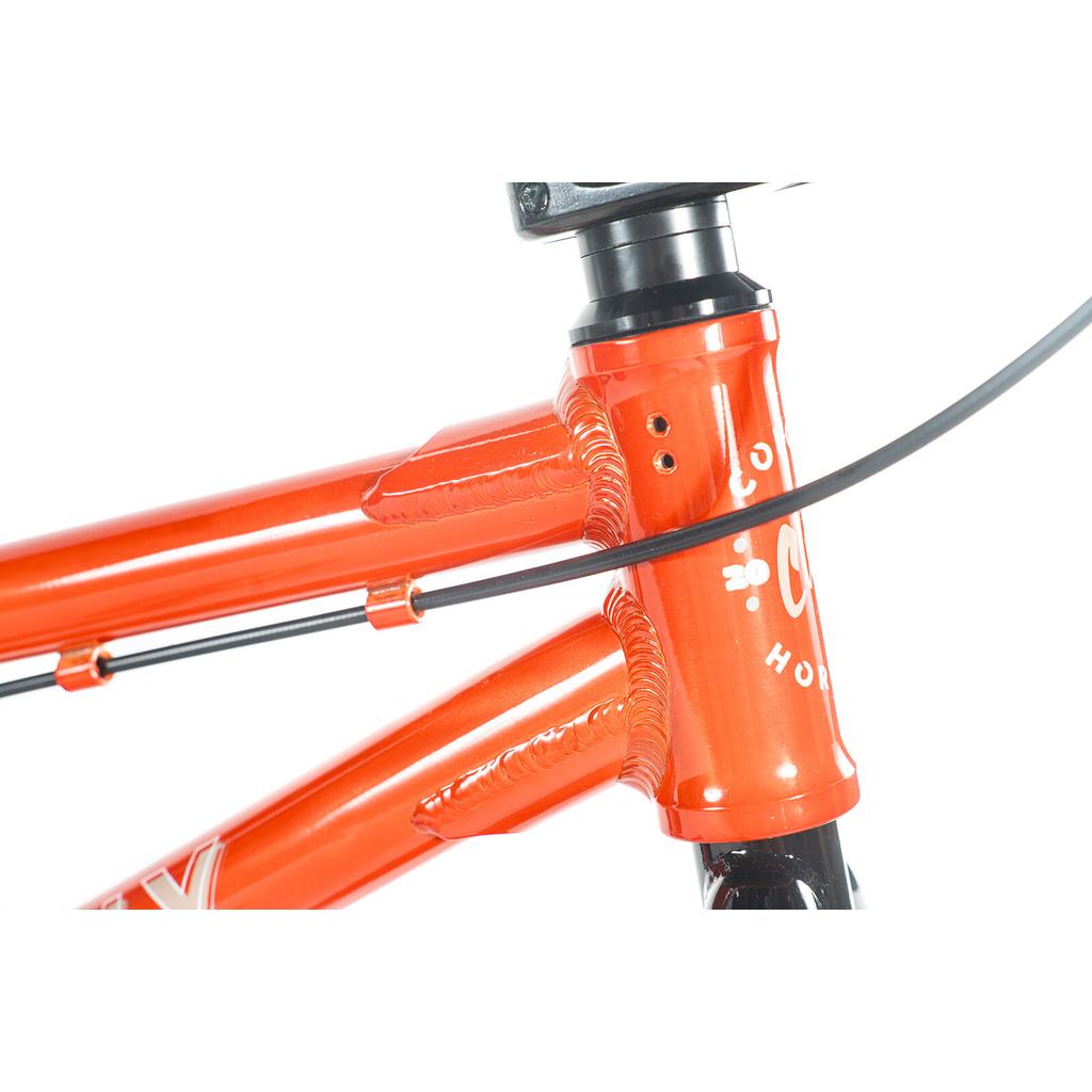 Close-up of the Colony Horizon 16 Inch Bike's orange head tube and frame with visible welds, logo, and a black cable across the front—ideal for freestyle riders.