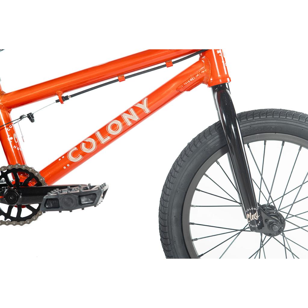 Close-up of the Colony Horizon 16 Inch Bike in orange, showcasing its frame, pedals, black fork, and front wheel—ideal for freestyle riders—set against a white background.