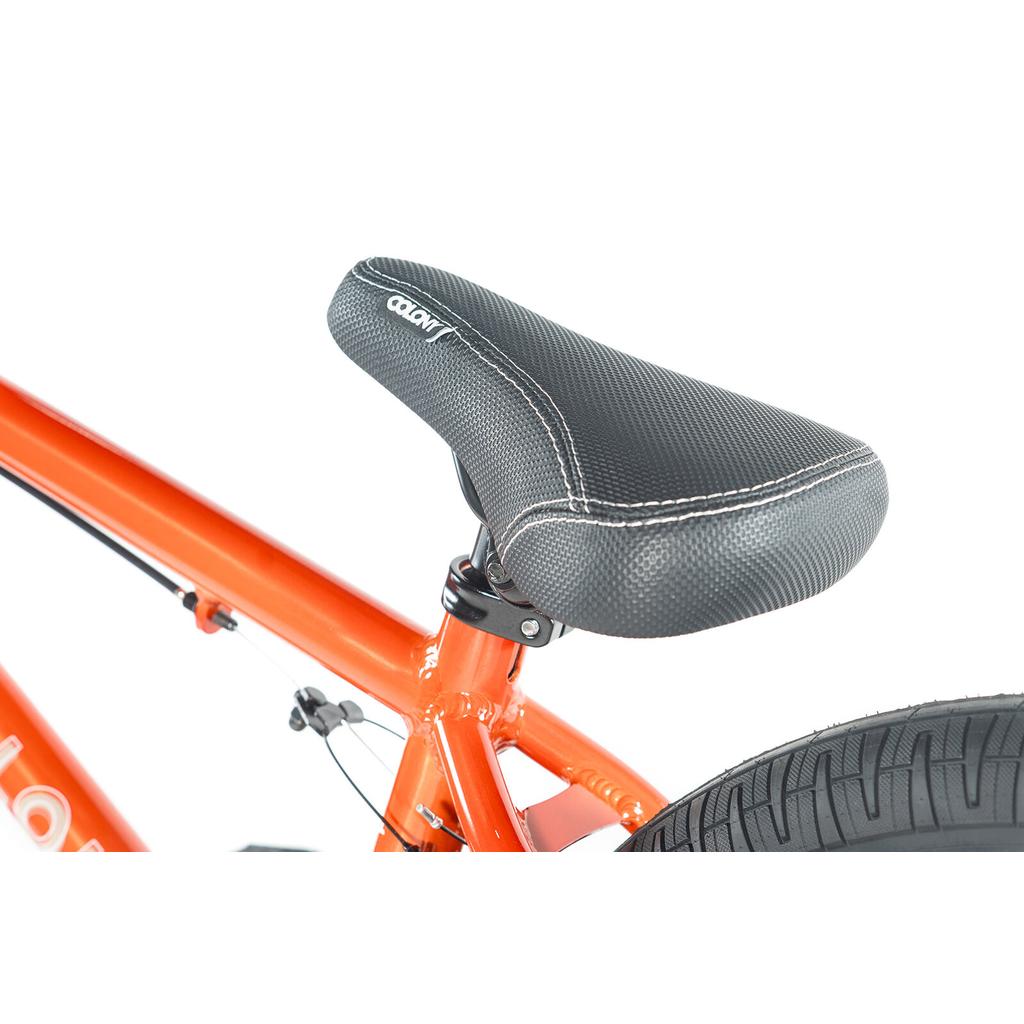 Close-up of a black seat on the Colony Horizon 20 Inch Bike's orange frame, with rear tire and brake cable visible—ideal for BMX enthusiasts and aspiring freestyle Olympic athletes.