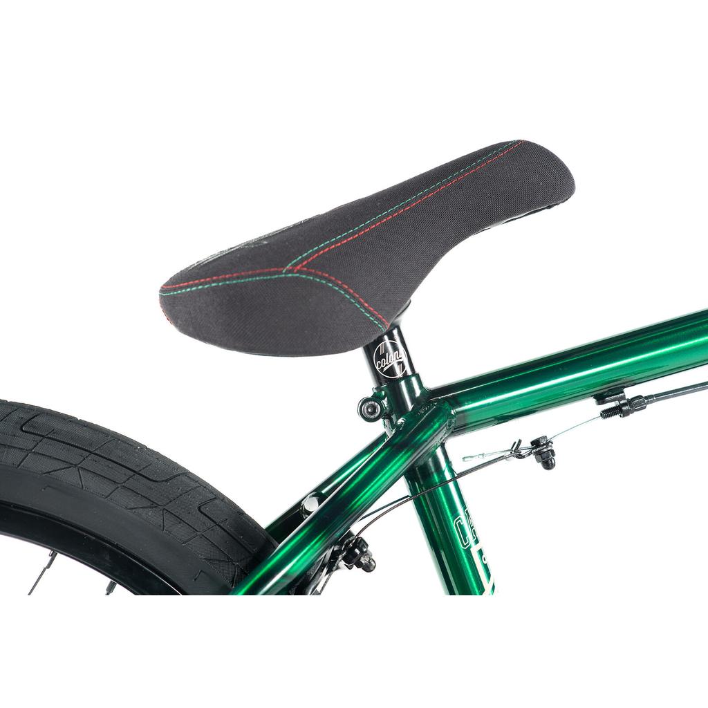Close-up of a black bicycle seat with red and green stitching on a metallic green Colony Cadet Elite 20 Inch Bike frame, with part of the rear wheel visible.