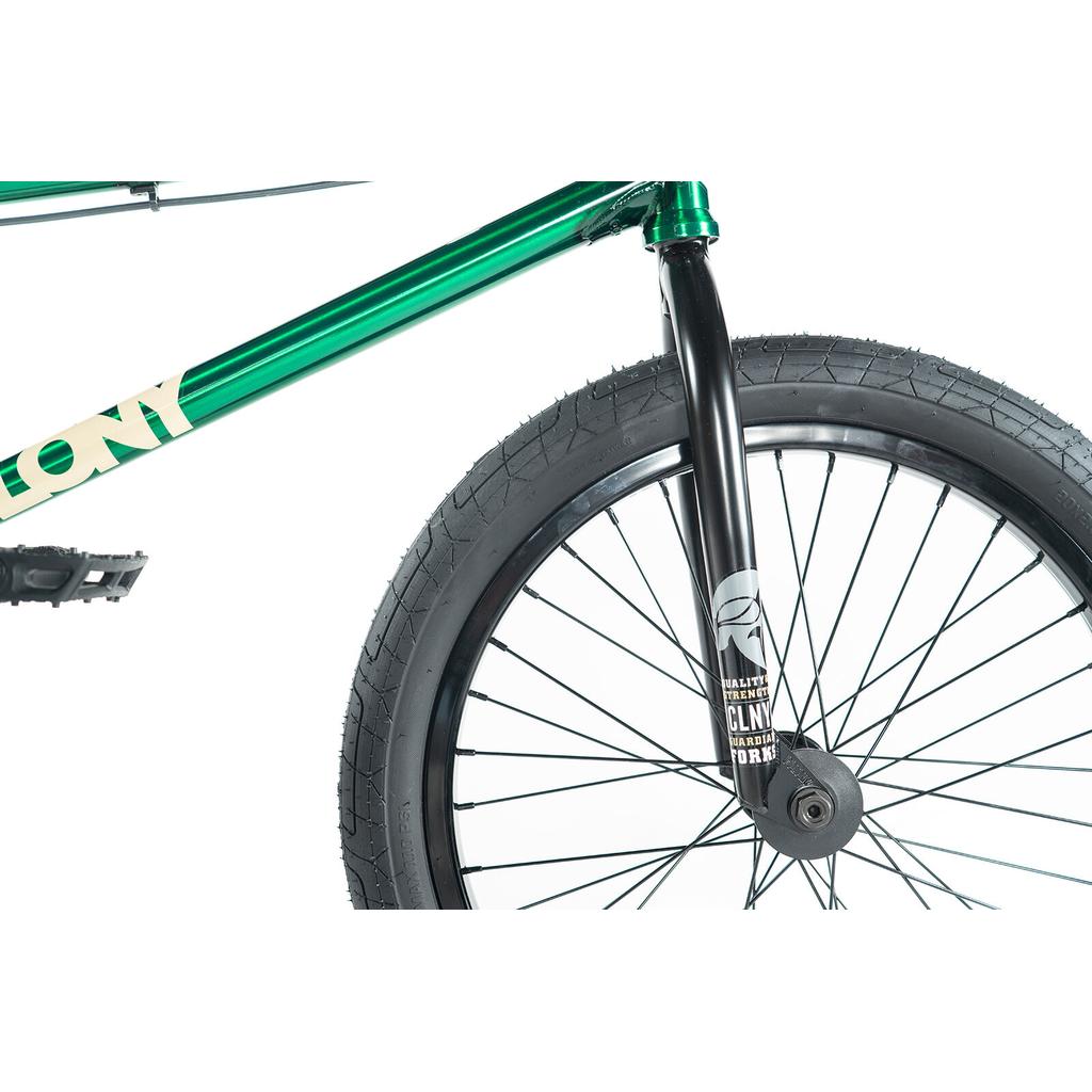 Close-up of the front section of a green Colony Cadet Elite 20 Inch Bike, showing the front wheel, black fork, tire, spokes, and part of the pedal against a white background.
