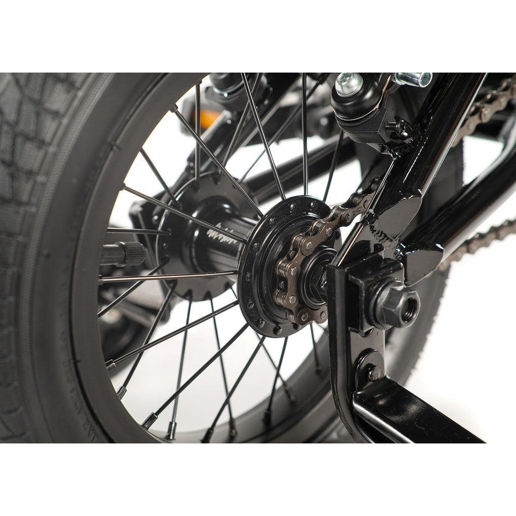 Close-up of a Division Blitzer 12 Inch Bike wheel and gear mechanism, highlighting the spokes, chain, and hub in detail—ideal for those diving into the excitement of entry-level freestyle BMX biking.