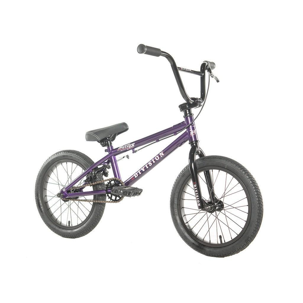 The Division Blitzer 16 Inch Bike showcases a striking purple frame complemented by robust tires, black handlebars, and a stylish black seat. This entry-level BMX bike is crafted with scaled-down geometry ideal for beginners, all presented against a crisp white backdrop.