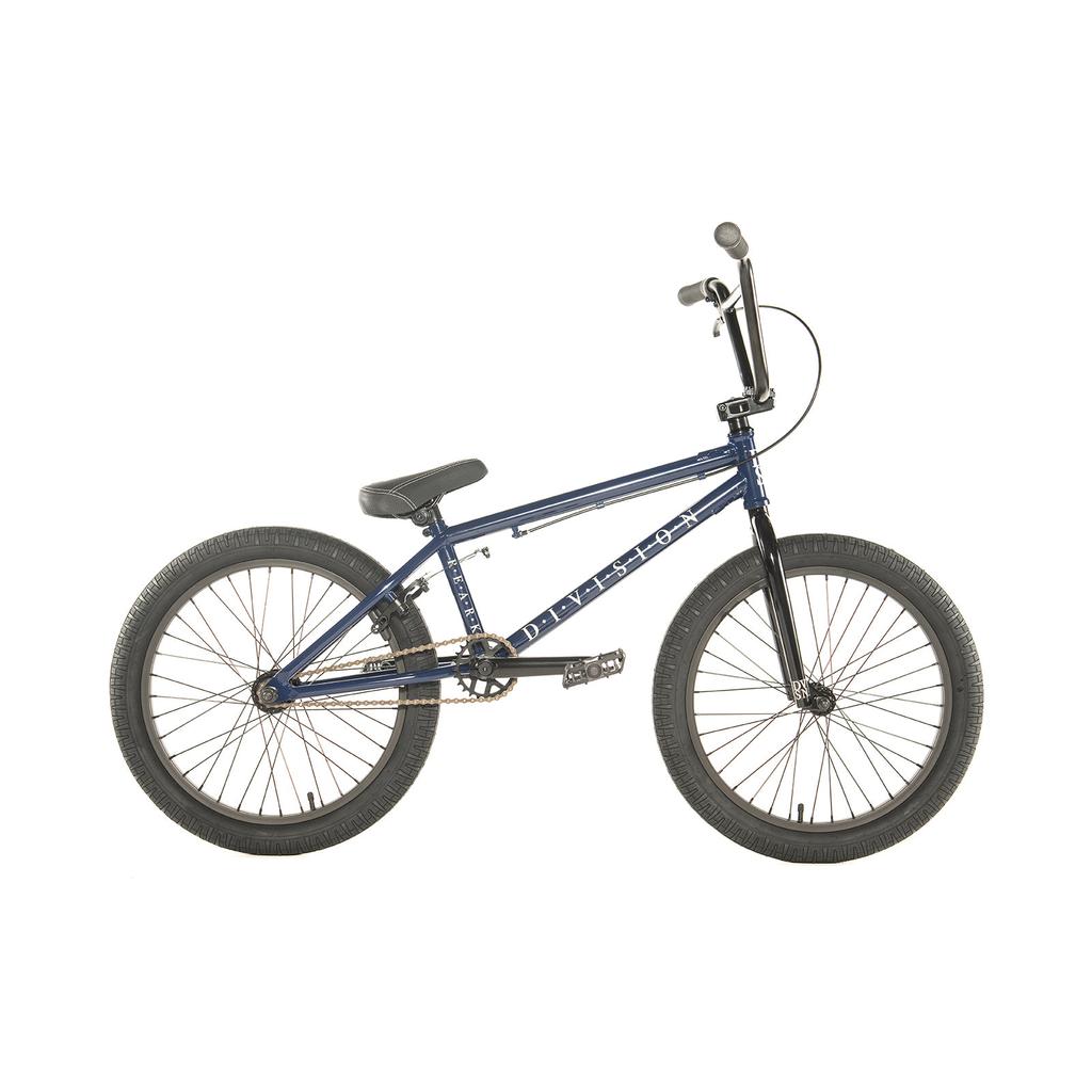 The Division Reark 20 Inch Bike is shown in side profile against a white background, featuring a blue frame, black handlebars, seat, and tires. Made from lightweight Hi-Tensile steel with durable 3-piece cranks.