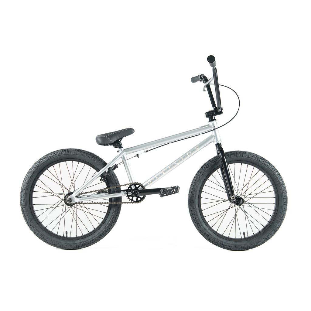 The Division Reark 20 Inch Bike is silver with black handlebars, seat, and tires. Shown in side view on a white background, it features durable 3-piece cranks and a sealed bottom bracket for smooth performance.