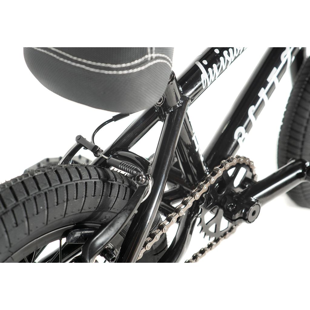 Close-up of the Division Blitzer 12 Inch Bike in black, highlighting the rear wheel, tire tread, chain, pedal, seat, and brake mechanism.
